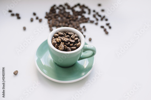 fresh morning coffee beans in a small espresso cup on a white background