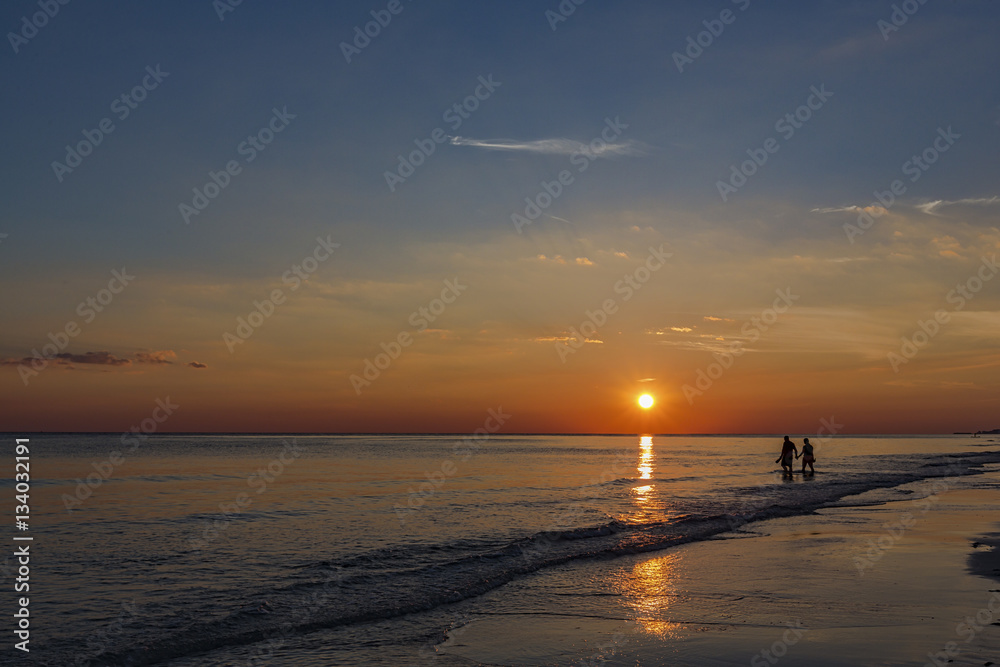 A couple wading in the Gulf of Mexico enjoying the sunset in Miramar Beach, Florida
