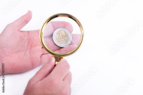 Hand with euro and magnified glass