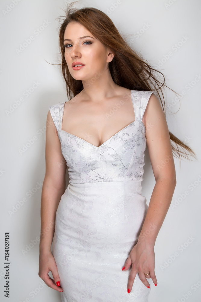 Half body woman portrait standing in white body-con dress isolated grey white background.. Half body woman portrait standing in white body-con dress isolated grey white background..
