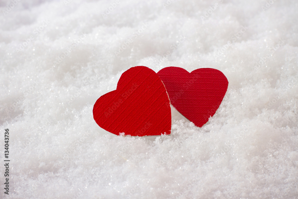 Obraz premium Two red hearts in snow