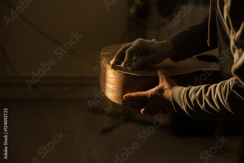 Serious professional guitar-maker working with unfinished guitar at workshop