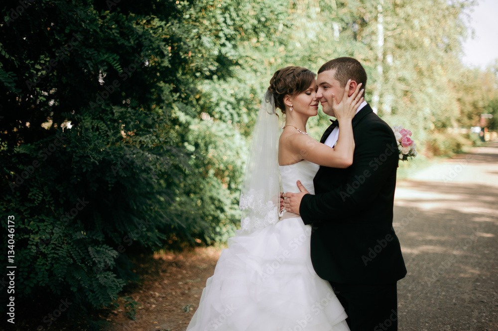 Elegant young happy wedding couple is sitting at green grass on Elegant young happy wedding couple is sitting at green grass on