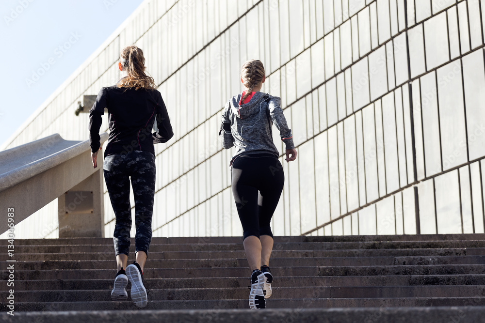 Two beautiful young women running in urban environment.