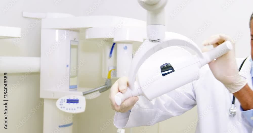 Dentist in lab coat adjusting light Dentist in lab coat adjusting light