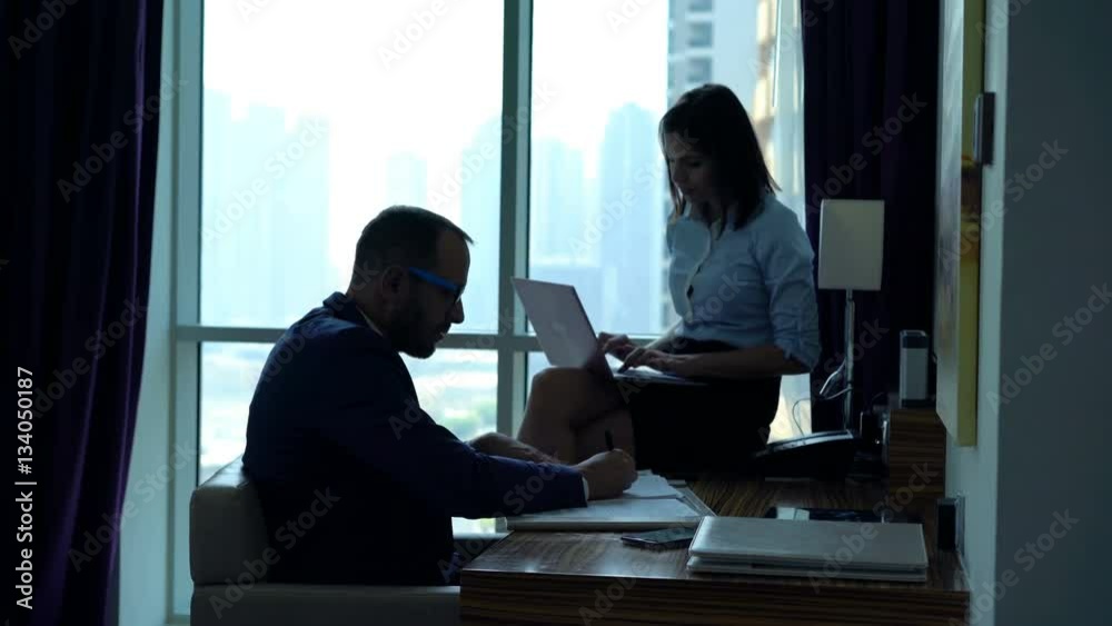 Businesspeople talking and working with laptop and documents in office
Businesspeople talking and working with laptop and documents in office