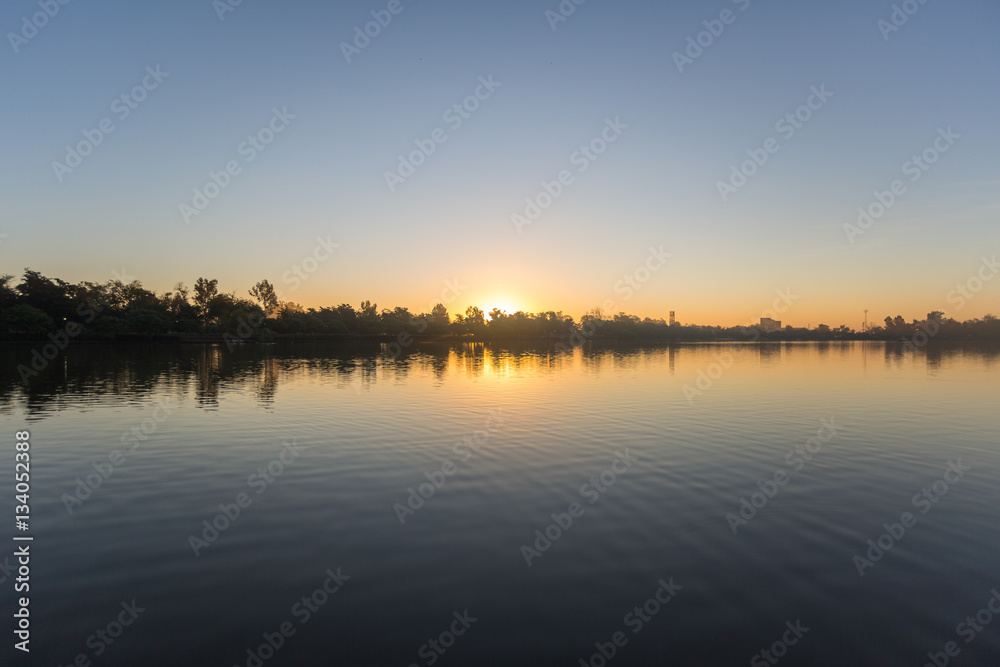 Sol ocultándose entre los árboles a la orilla de un lago