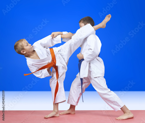 Two athletes in karategi beat kick arm and leg