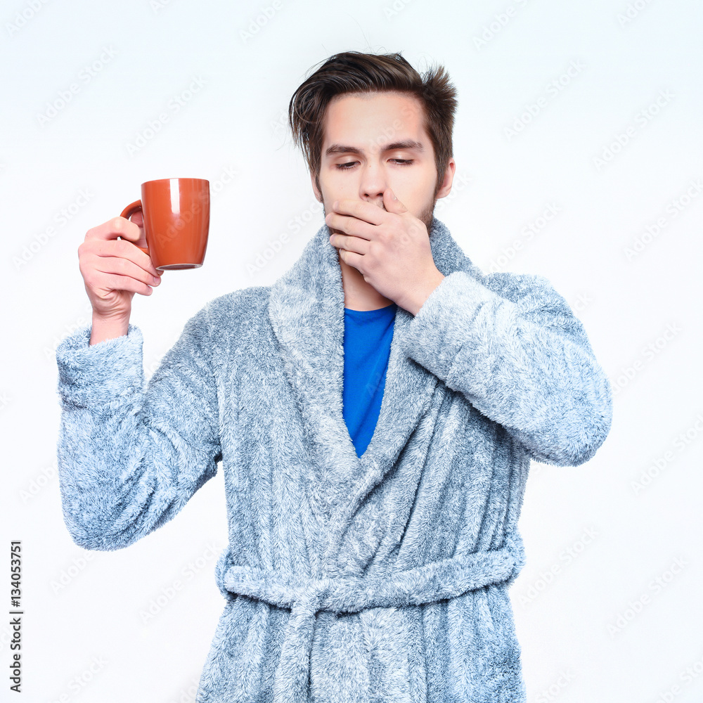 handsome bearded yawning sleepy man with cup in terry bathrobe handsome bearded yawning sleepy man with cup in terry bathrobe
