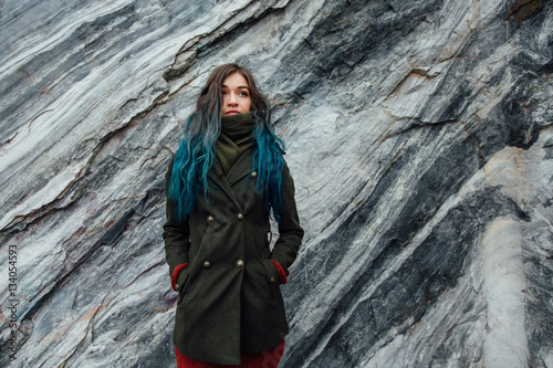 Portrait of a beautiful hipster girl on the background the rocky cliffs. Dyed hair, blue, long.