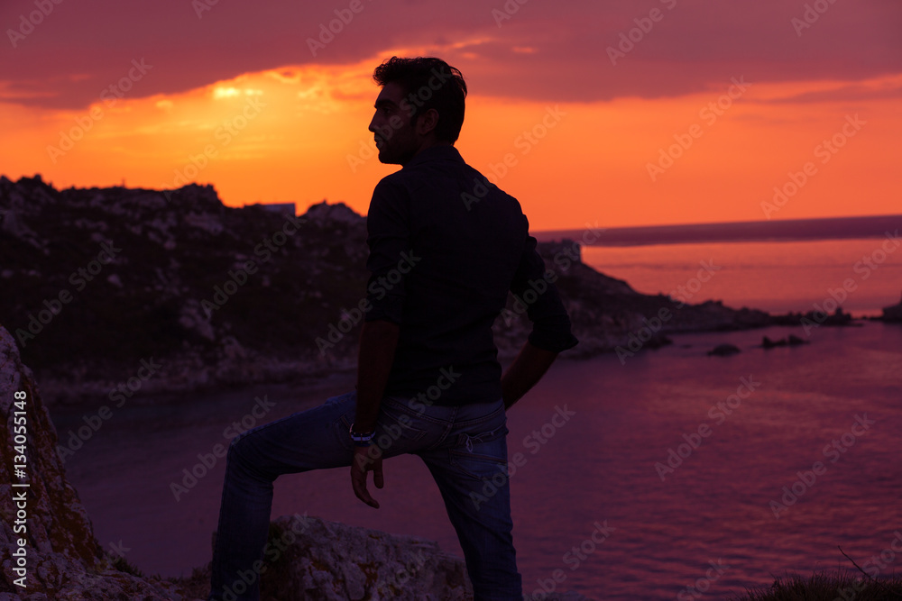 Fototapeta premium man standing thinking back light sunset lighting side view profile silhouette summer evening beach