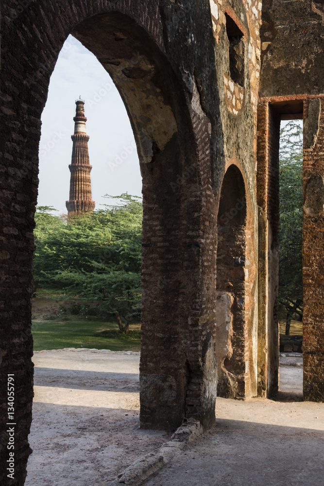 Qutub Minar as seen through ruins of mehrauli archaeological park in Mehrauli, Delhi, India, Asia.