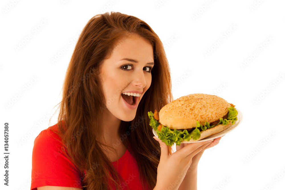 Unhealthy meal - happy young woman eats hamburger isolated over Unhealthy meal - happy young woman eats hamburger isolated over