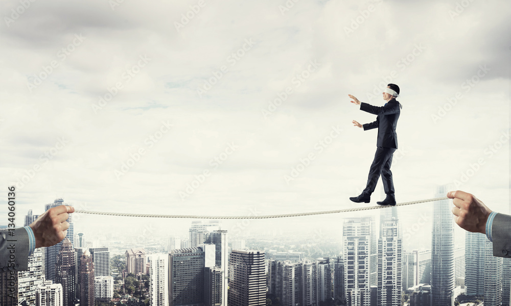 Business concept of risk support and assistance with man balancing on rope Business concept of risk support and assistance with man balancing on rope