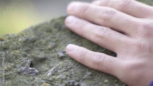 Men's hand touching the stone in slow motion photo