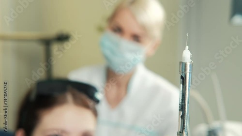 Dentist releases air from syringe to make patient injection. On the front palne injection with drug for anesthesia in dental clinic. Stomotologist blonde in white coat uniform, following process photo