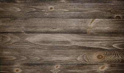 Old weathered wood surface with long boards lined up. Wooden planks on a wall or floor with grain and texture. Dark neutral tones with contrast.