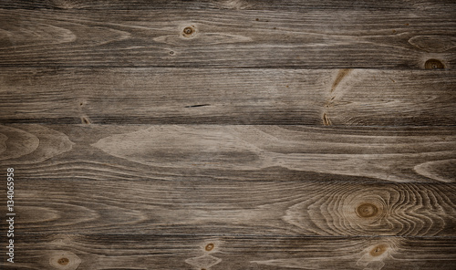 Old weathered wood surface with long boards lined up. Wooden planks on a wall or floor with grain and texture. Dark neutral tones with contrast.