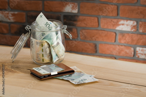 cienki portfel z polskimi banknotami i kartami płatniczymi na ceglanym tle