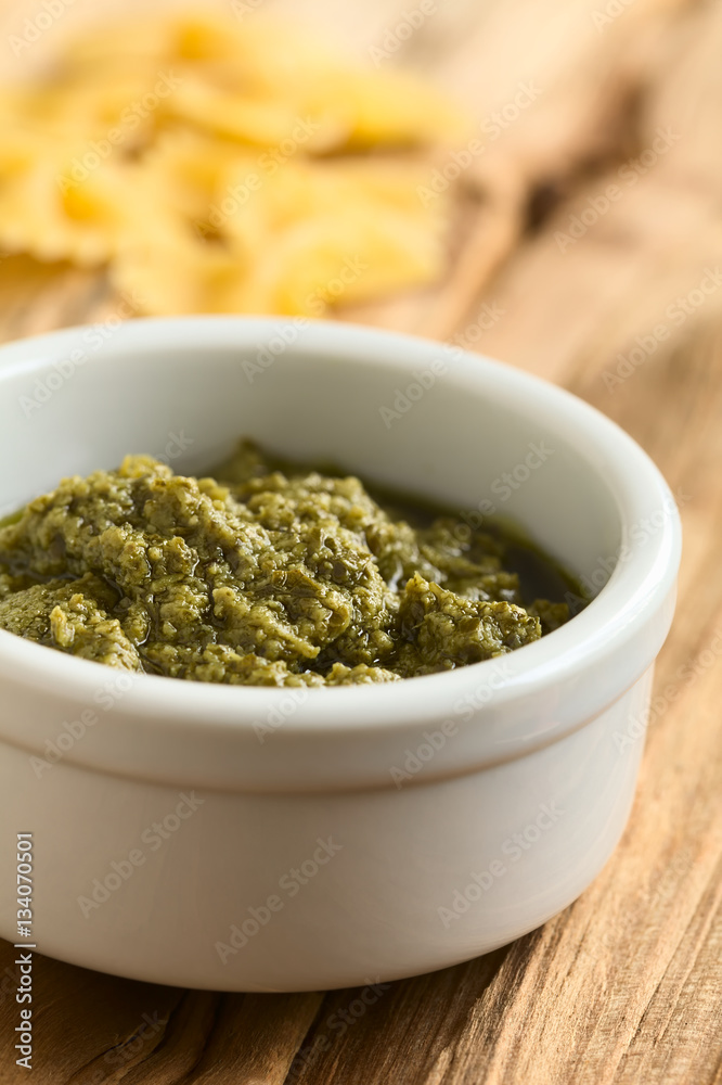 Pesto alla genovese made of basil, garlic, olive oil, pine nuts and cheese, photographed on wood with natural light (Selective Focus, Focus one third into the pesto) Pesto alla genovese made of basil, garlic, olive oil, pine nuts and cheese, photographed on wood with natural light (Selective Focus, Focus one third into the pesto)