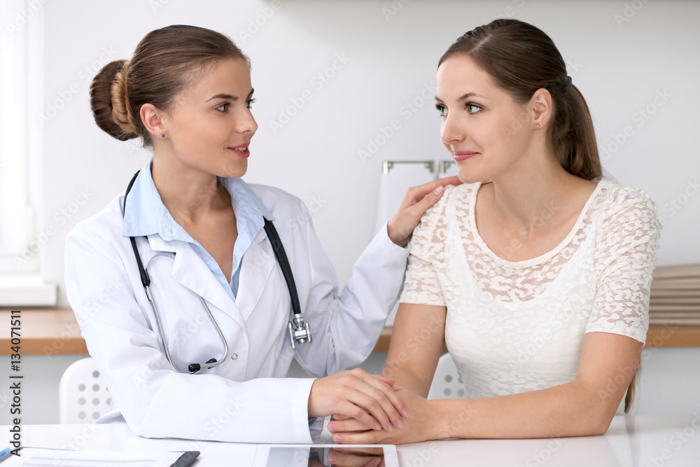 Doctor reassuring her female patient while sitting at the desk. Medicine, help and health care concept Doctor reassuring her female patient while sitting at the desk. Medicine, help and health care concept