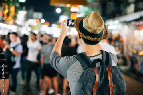 Young Asian traveler taking photo with mobile phone in Khaosan road