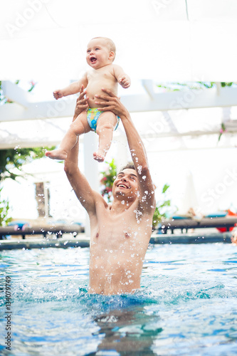 father plays with the baby boy in the pool
