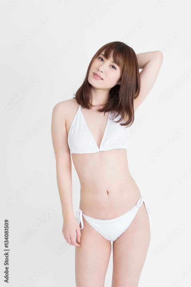 白いセパレートの水着を着た若い女性。スタジオ撮影。白背景。 白いセパレートの水着を着た若い女性。スタジオ撮影。白背景。