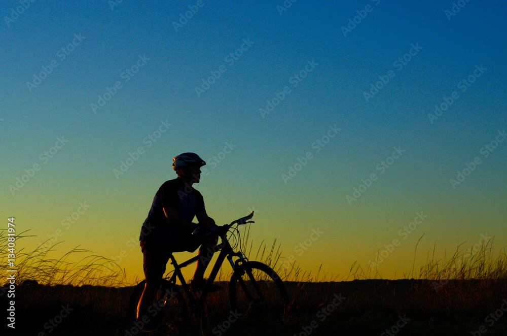 Adult cyclist silhouette having rest dusk time