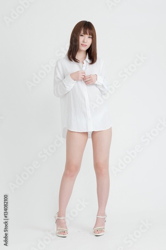 白いシャツを着た女性。女性は足の素肌を見せています。スタジオ撮影。白背景。