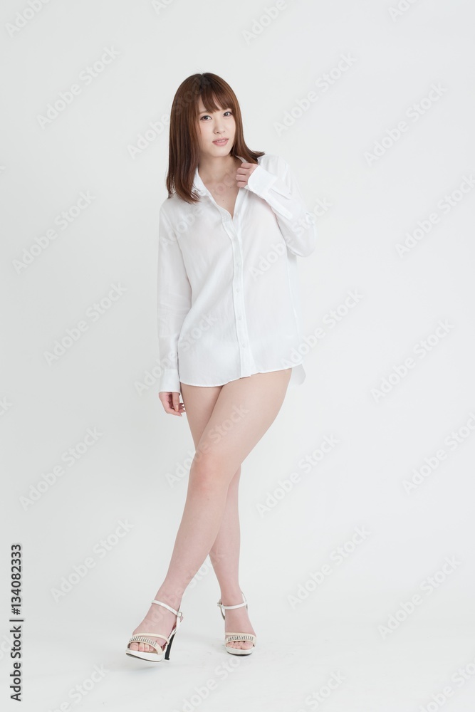 白いシャツを着たセクシーな女性。この女性は、脚の素肌を見せています。スタジオ撮影、白背景。 白いシャツを着たセクシーな女性。この女性は、脚の素肌を見せています。スタジオ撮影、白背景。