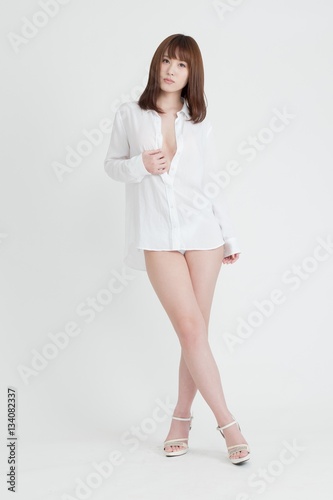 白いシャツを着たセクシーな女性。この女性は、脚の素肌を見せています。スタジオ撮影、白背景。