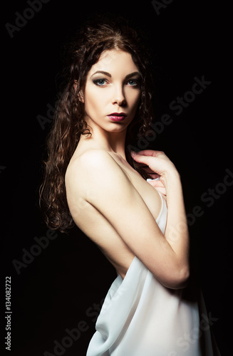 Dramatic portrait of sensual young woman among darkness