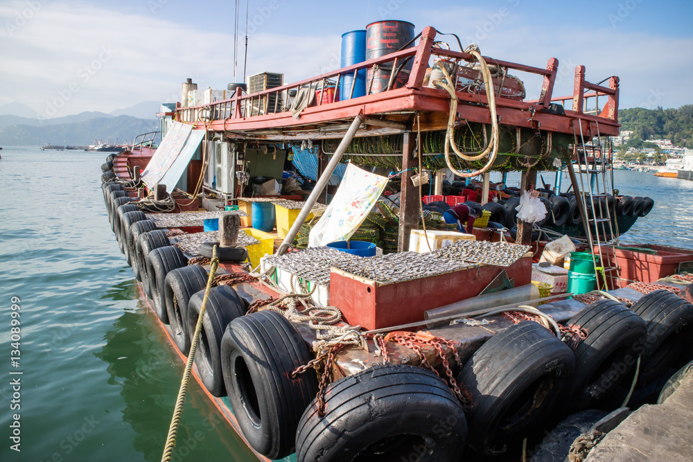 Fishing boat and its drying fish under the sun