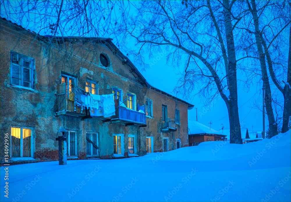 Winter landscape with old retro building with lightning in windo