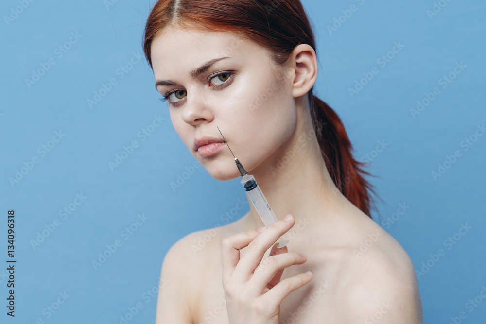 woman with a syringe on a blue background, rejuvenating injection, lifting woman with a syringe on a blue background, rejuvenating injection, lifting