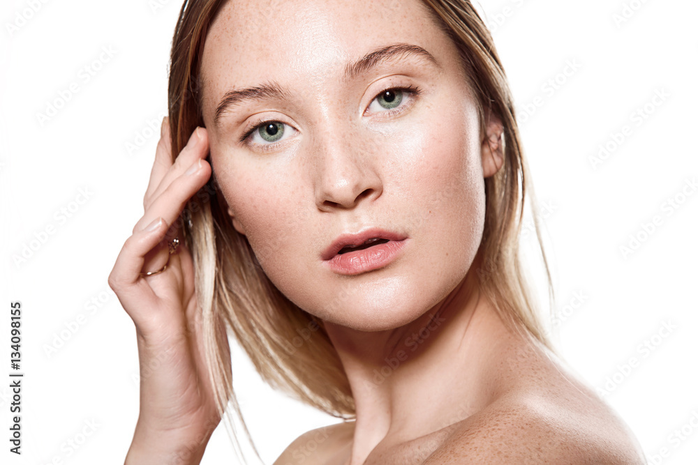 Beautiful young woman with freckles on her face with a light sensitive skin. Portrait with bare shoulders on a white background Beautiful young woman with freckles on her face with a light sensitive skin. Portrait with bare shoulders on a white background