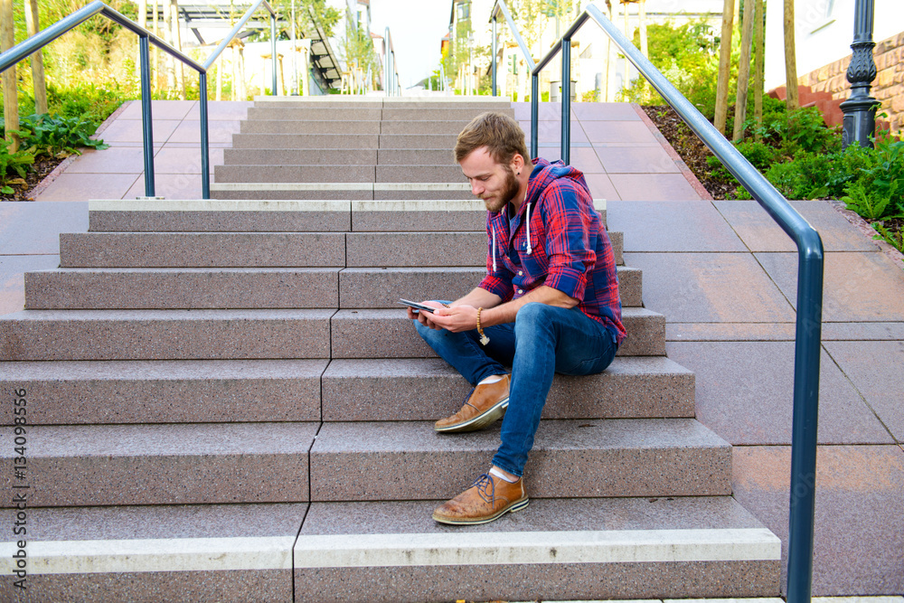 young man sitting on stairs and using tablet PC young man sitting on stairs and using tablet PC
