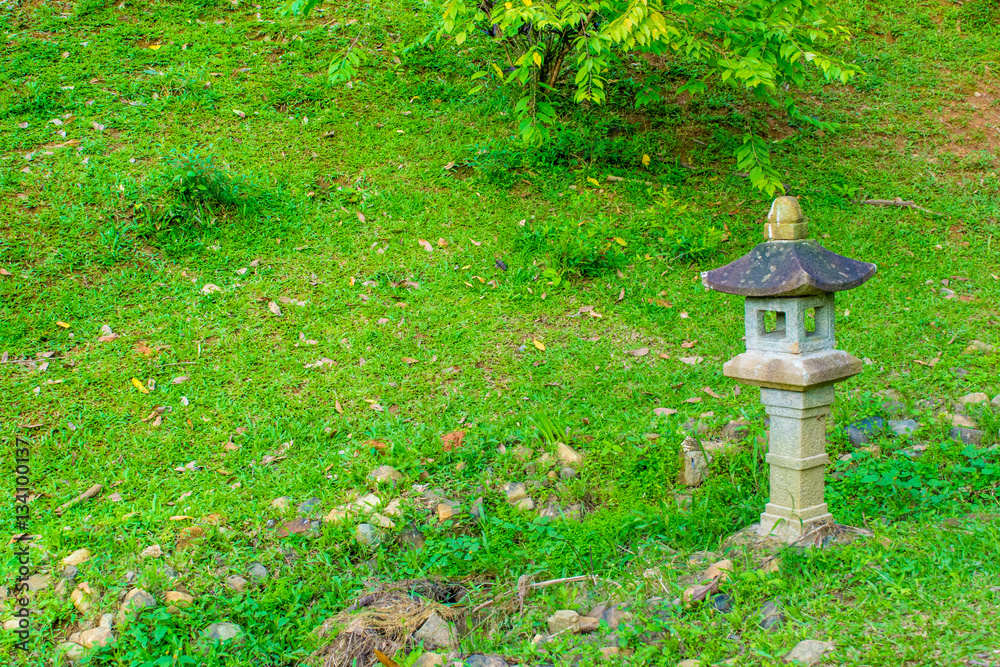 Asian traditional lamp in a garden with lush lawn