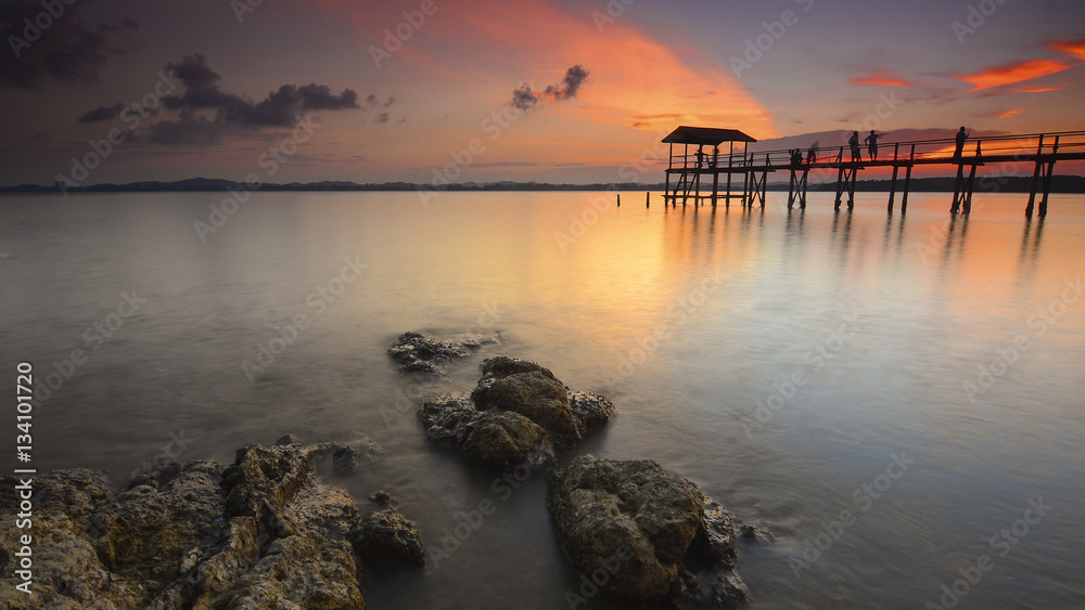 Obraz premium Beautiful sunset reflections with silhouette peoples on the jetty