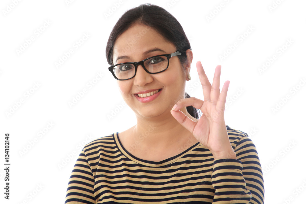 Cheerful young woman showing OK sign against a white background Cheerful young woman showing OK sign against a white background