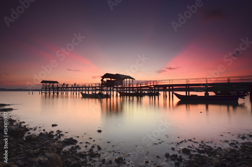 Beautiful sunset over wooden jetty with silhoutte of man fishing © nelzajamal