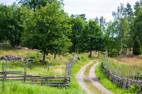 Gravel road in a rural landscape in the countryside with meadows surrounded with wooden fences in summer. photo