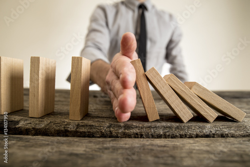 Businessman halting the domino effect photo