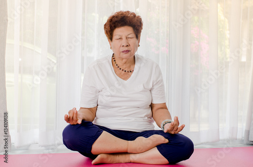 Senior woman making meditating at home.