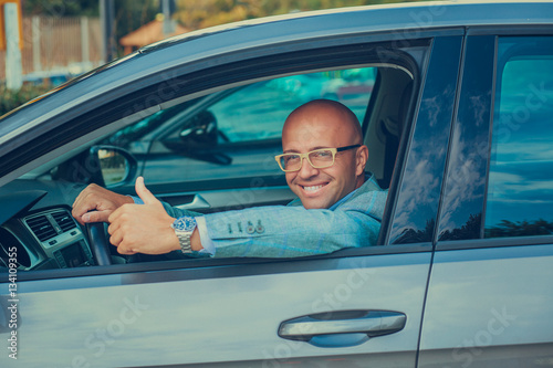 Business man in his car smiling, showing thumbs up