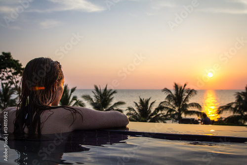 Frau genie  t im Pool den romantischen Sonnenuntergang