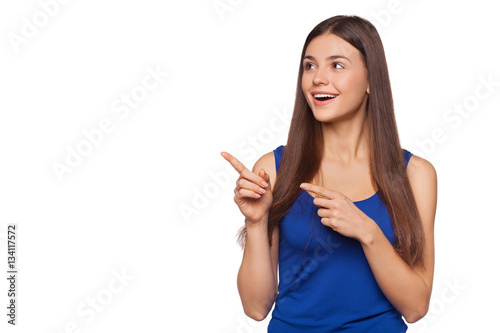 Smiling excited woman showing finger on copy space for product or text, isolated over white background