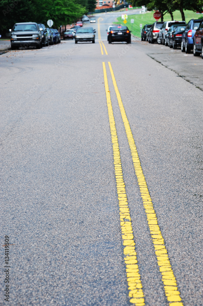 double yellow line in urban street with cars parking along the street