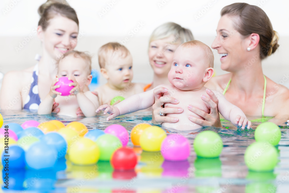 Mothers and sucklings at baby swim course playing with balls Mothers and sucklings at baby swim course playing with balls